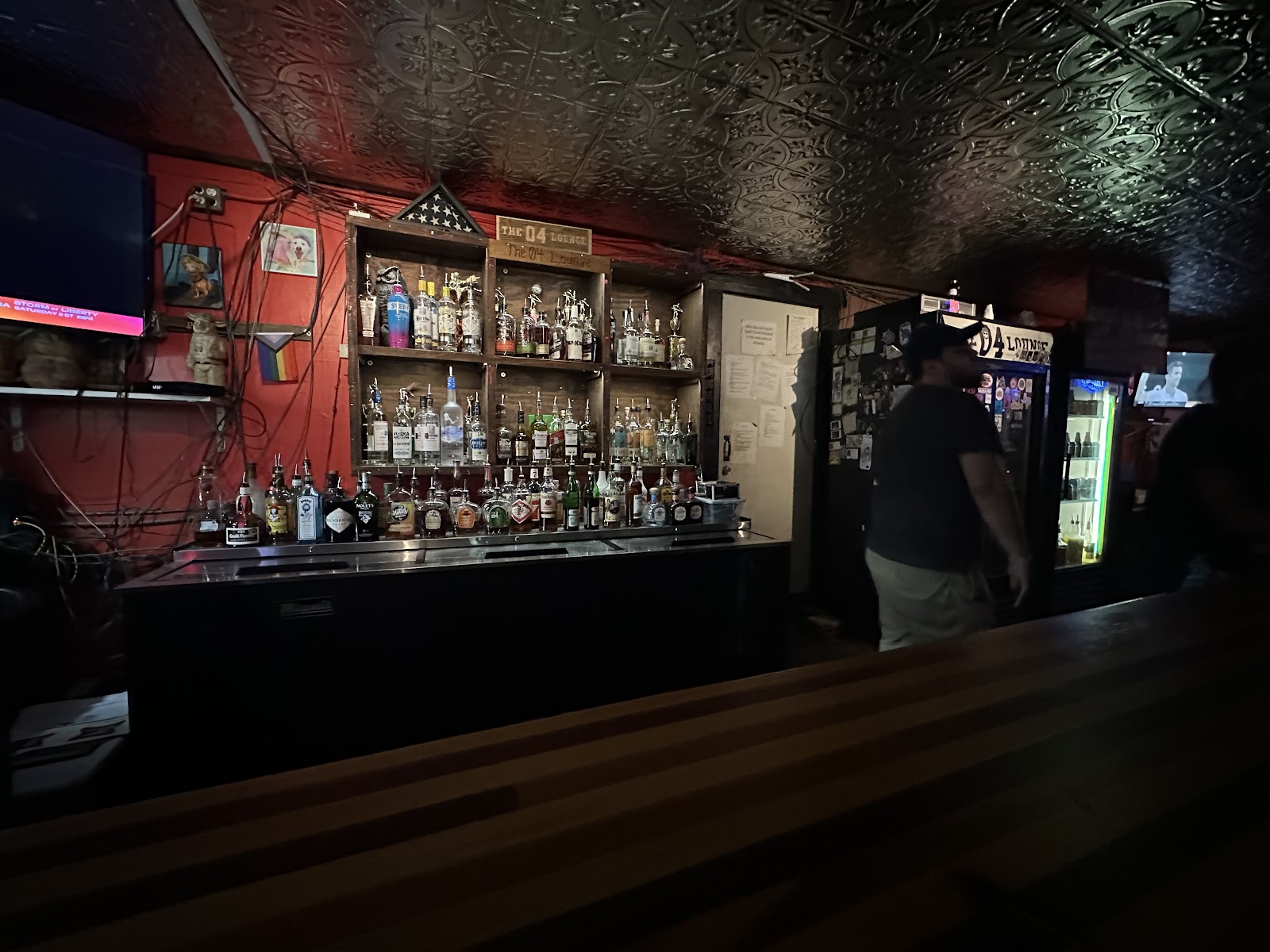 The back bar at night, tin ceiling, bottles, and the cooler.