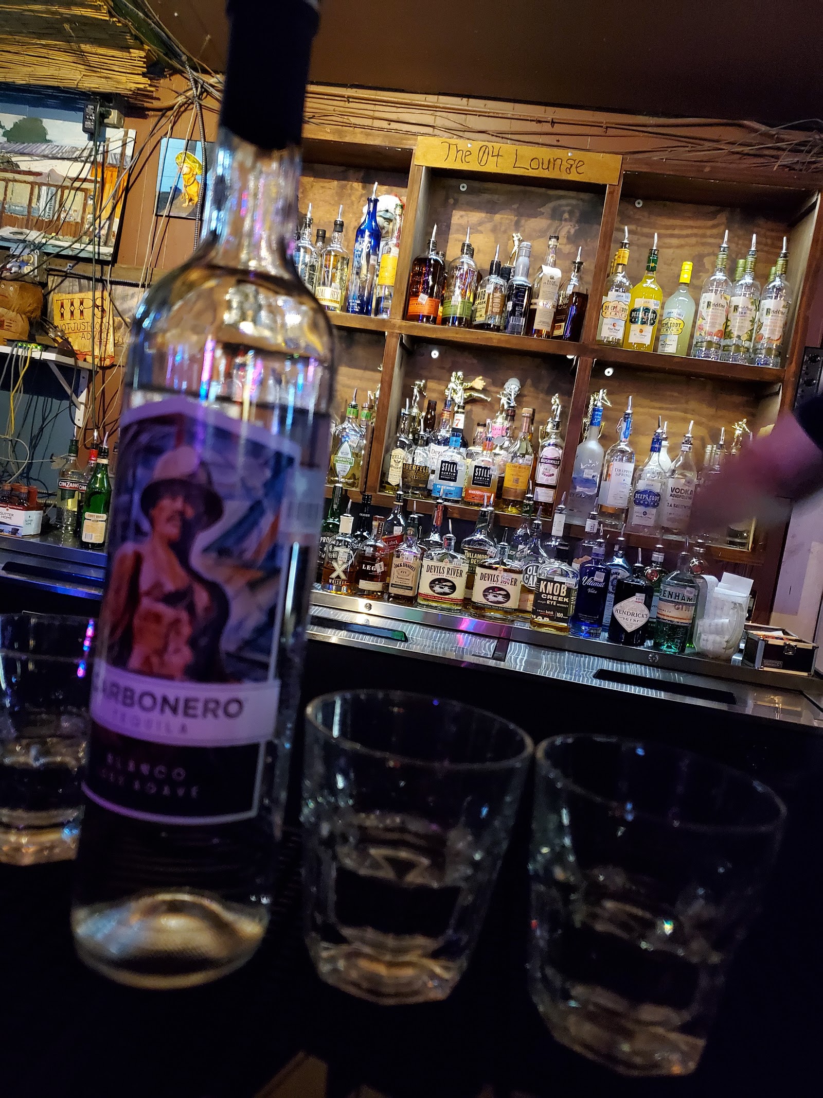 A pour on the bar with the 04 Lounge shelves behind the glasses.