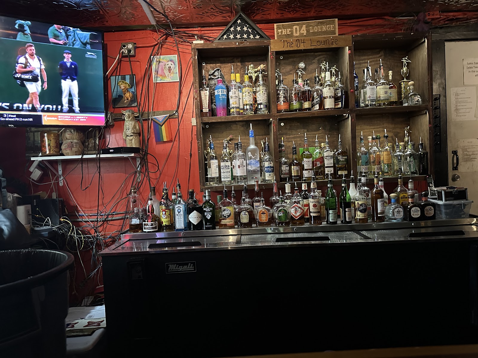 Back bar: red wall, wood shelves of bottles, and the 04 Lounge sign.