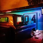 Night shot from @the04lounge: the blue wall, the number 04, and an old truck in the lot.